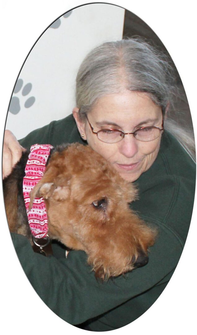 A woman hugging a crying Airedale terrier (Charlotte)