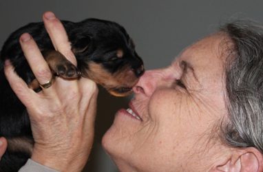 A woman holding a pup to her nose