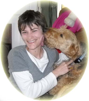An Airedale terrier licking a womans face